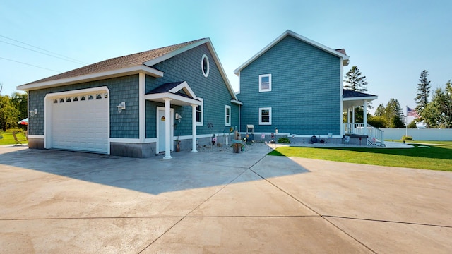 rear view of property featuring a porch, a yard, and a garage