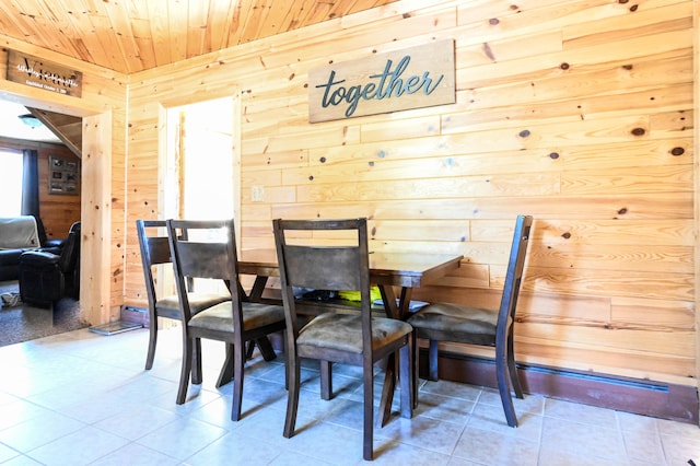 dining area featuring wood ceiling, light tile flooring, and wood walls