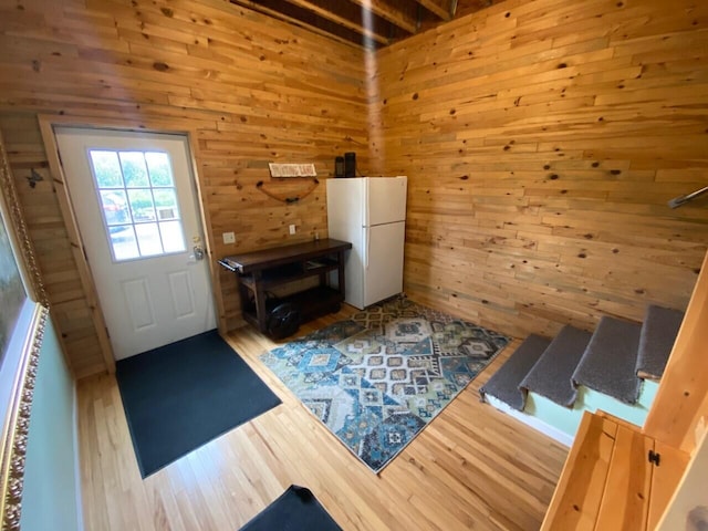 foyer entrance featuring wood walls and light hardwood / wood-style floors