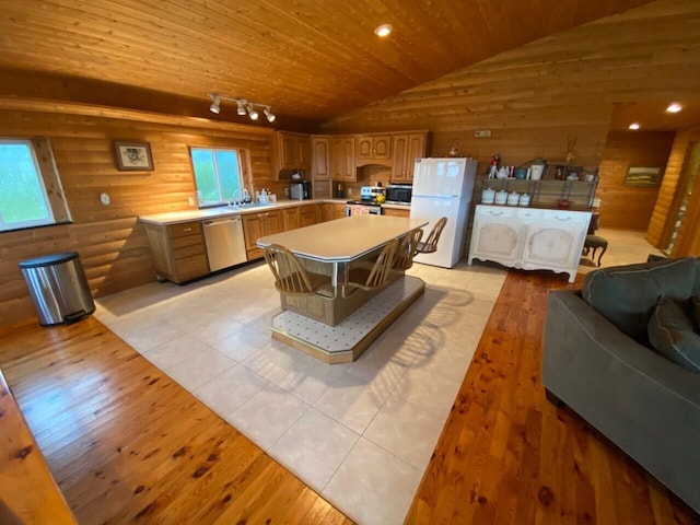 interior space with wooden ceiling, rail lighting, lofted ceiling, sink, and rustic walls