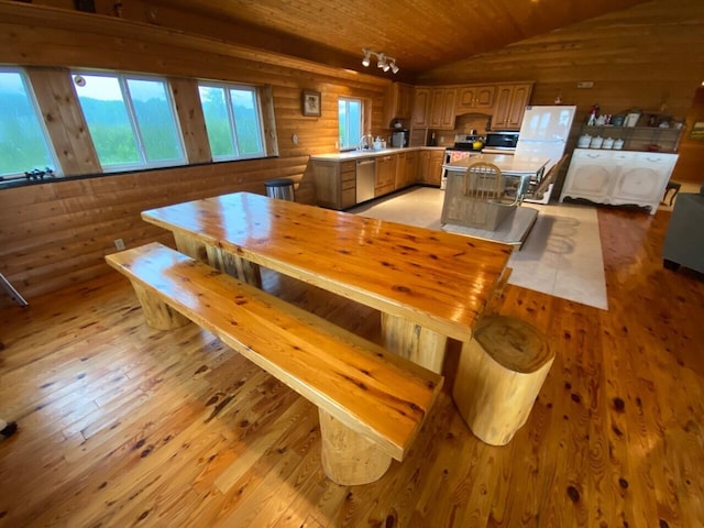 dining area featuring light wood-type flooring, sink, and lofted ceiling