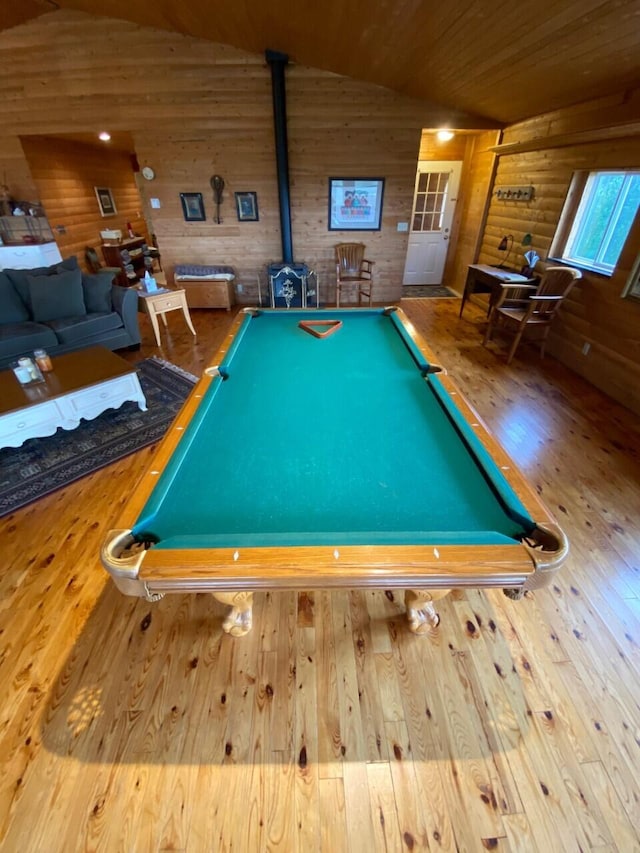 game room featuring a wood stove, light hardwood / wood-style flooring, pool table, and vaulted ceiling