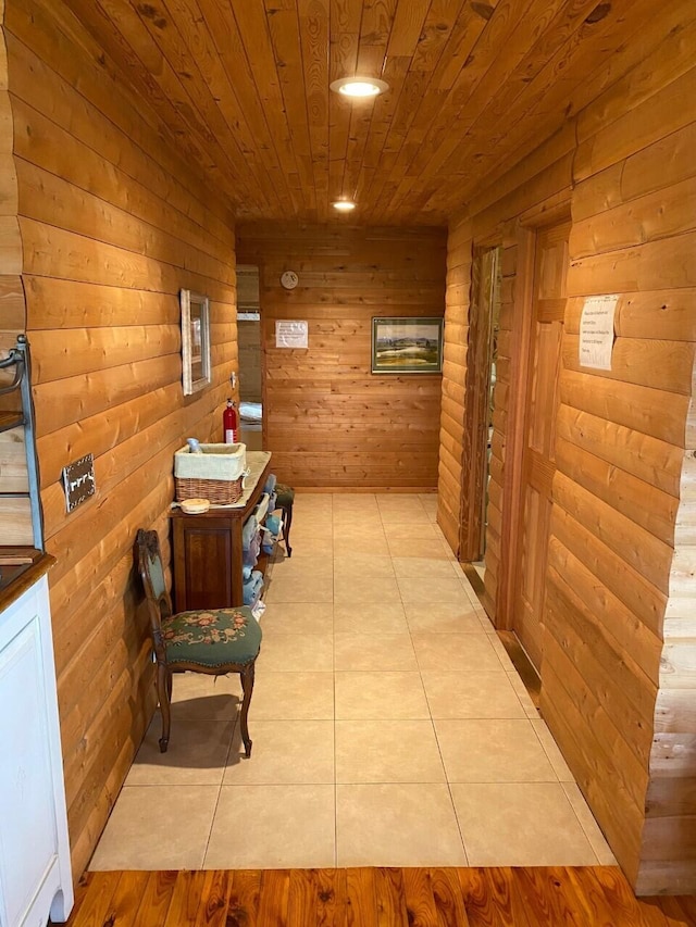 hall featuring wooden walls, wooden ceiling, and light tile floors