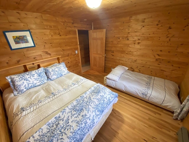 bedroom featuring wooden walls, wooden ceiling, and light hardwood / wood-style flooring