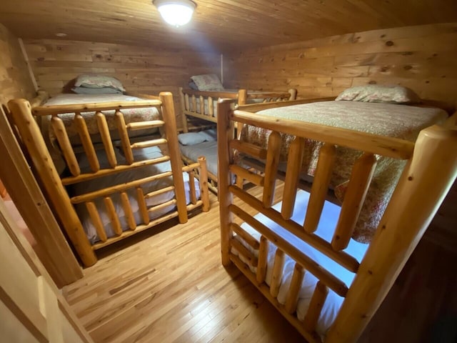 bedroom featuring wooden walls, wooden ceiling, and light hardwood / wood-style flooring