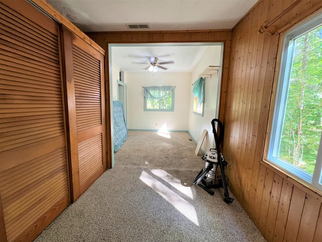 hallway featuring wooden walls and light colored carpet