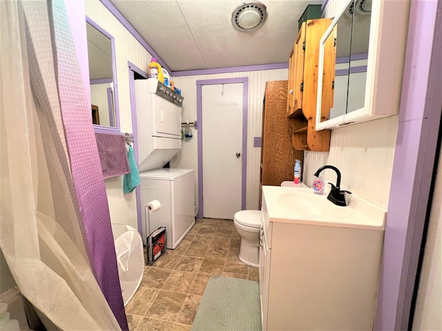 full bathroom with tile floors, toilet, vanity with extensive cabinet space, stacked washer and dryer, and shower / tub combo with curtain