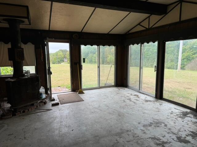 unfurnished sunroom with lofted ceiling and a wood stove