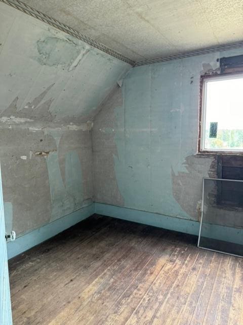 bonus room with dark hardwood / wood-style floors and vaulted ceiling