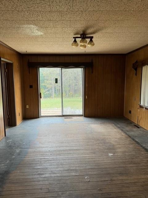 unfurnished living room featuring hardwood / wood-style flooring and wooden walls