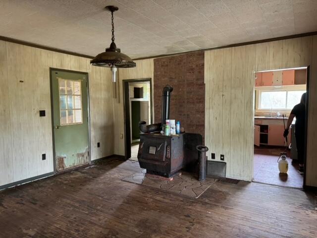 interior space featuring ornamental molding, a wood stove, wooden walls, and dark hardwood / wood-style floors