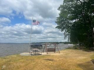 view of dock with a water view and a lawn