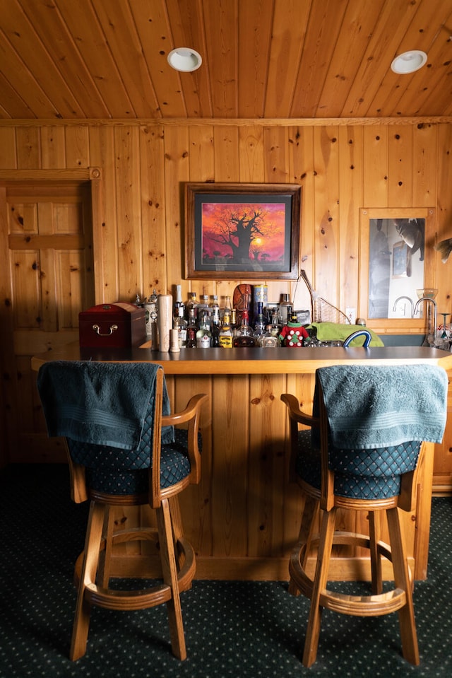 bar featuring wood ceiling, wooden walls, and sink