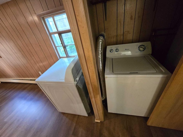 washroom with wooden walls, washing machine and dryer, and dark hardwood / wood-style floors