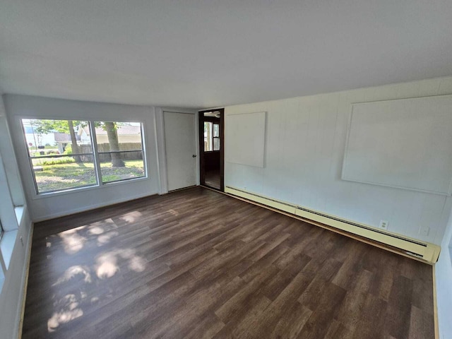 empty room with hardwood / wood-style flooring and a baseboard heating unit