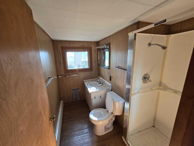 bathroom featuring a shower, wooden walls, toilet, vanity, and hardwood / wood-style flooring