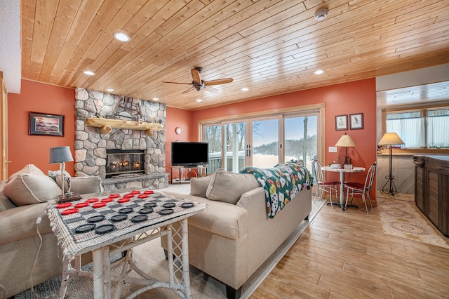 living room featuring ceiling fan, light hardwood / wood-style flooring, a fireplace, and wood ceiling