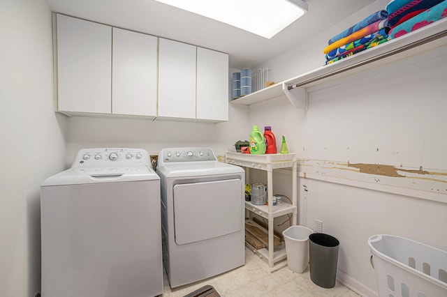 washroom with washing machine and clothes dryer, cabinets, and light tile floors