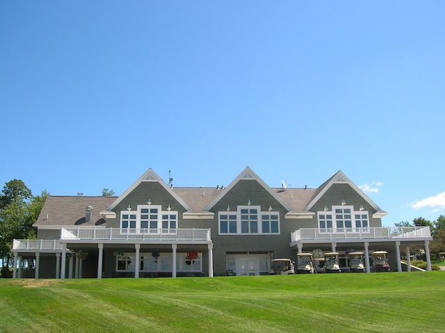 back of property with a balcony, a lawn, and a garage