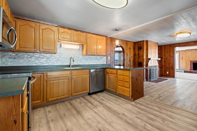 kitchen featuring light hardwood / wood-style flooring, backsplash, decorative light fixtures, wooden walls, and appliances with stainless steel finishes