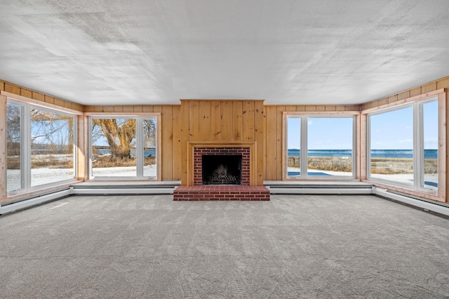 unfurnished living room featuring carpet, a water view, a wealth of natural light, and a fireplace