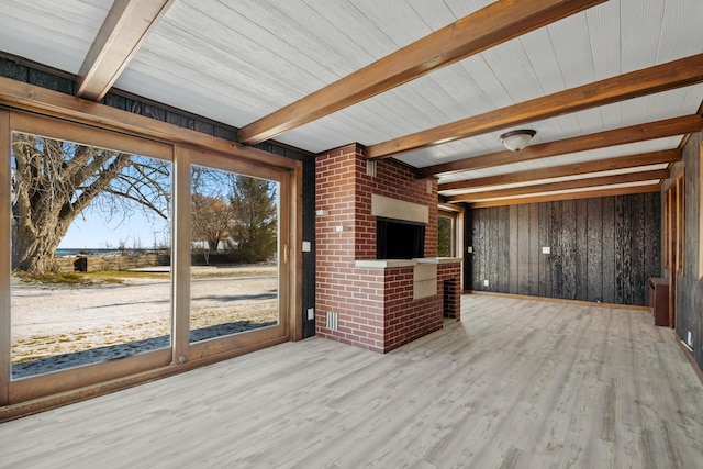 unfurnished living room with wooden ceiling, beam ceiling, light hardwood / wood-style floors, and wooden walls