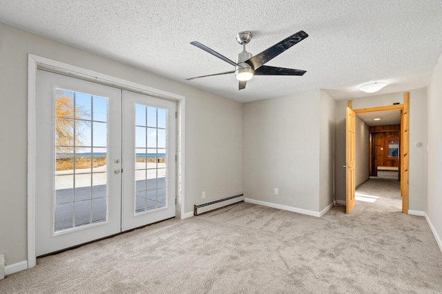 carpeted spare room featuring baseboard heating, ceiling fan, french doors, and a textured ceiling