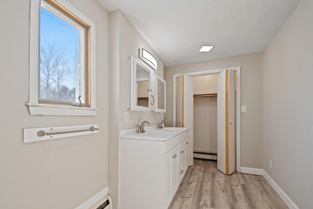 bathroom featuring hardwood / wood-style floors, vanity, a textured ceiling, and a baseboard heating unit