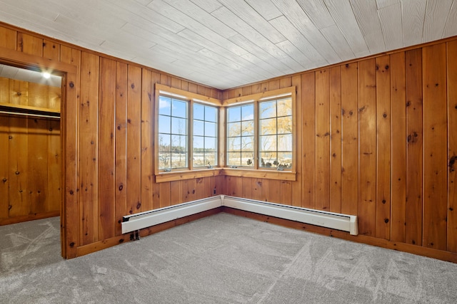 carpeted empty room featuring wooden walls and a baseboard radiator