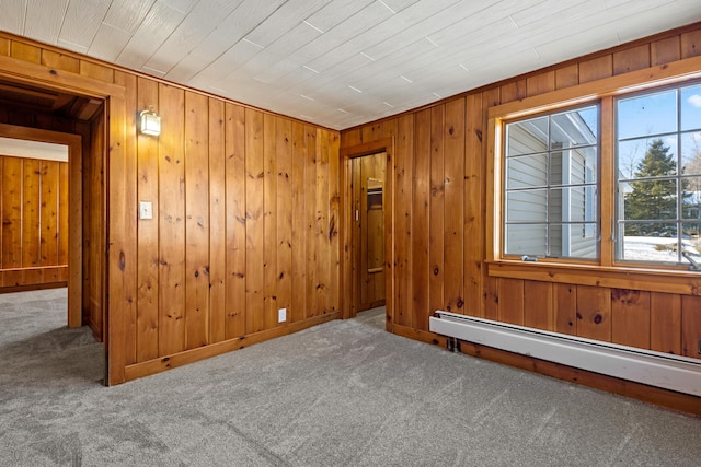 carpeted empty room with a baseboard radiator and wooden walls