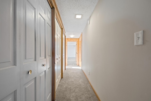 hall featuring a textured ceiling and light colored carpet