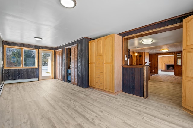 unfurnished living room featuring a fireplace, light hardwood / wood-style floors, and wooden walls