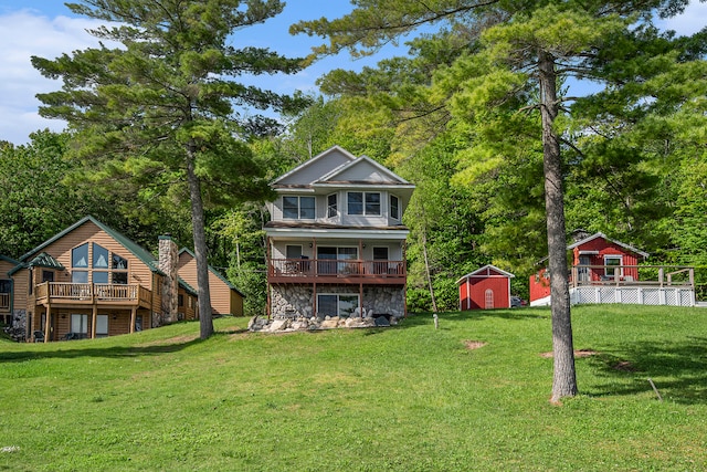 rear view of property featuring a wooden deck, a shed, and a lawn