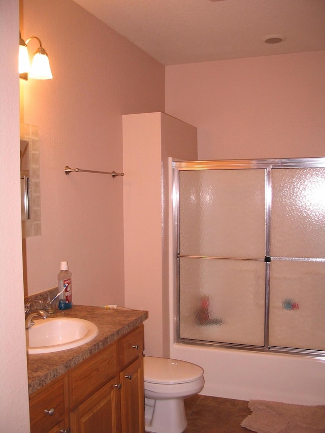 full bathroom with enclosed tub / shower combo, toilet, tile flooring, and oversized vanity