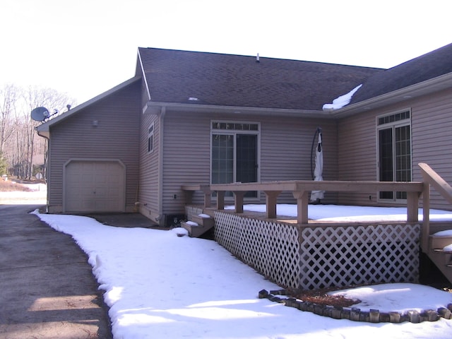 snow covered house featuring a garage