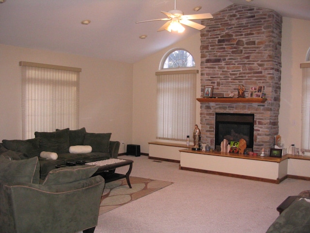 living room with a stone fireplace, ceiling fan, light carpet, and vaulted ceiling