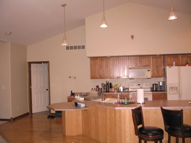 kitchen with hardwood / wood-style flooring, sink, high vaulted ceiling, white appliances, and hanging light fixtures