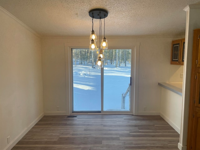 unfurnished dining area with dark hardwood / wood-style floors, a notable chandelier, a textured ceiling, and ornamental molding