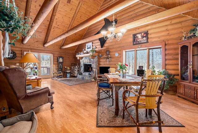 dining space featuring wood ceiling, a stone fireplace, beamed ceiling, and light hardwood / wood-style floors