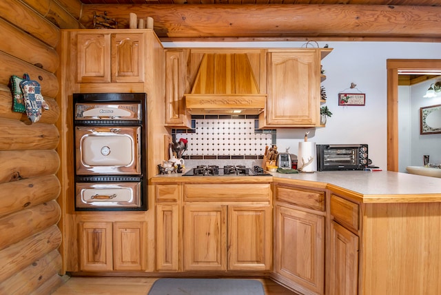 kitchen with gas cooktop, kitchen peninsula, rustic walls, custom exhaust hood, and light hardwood / wood-style floors