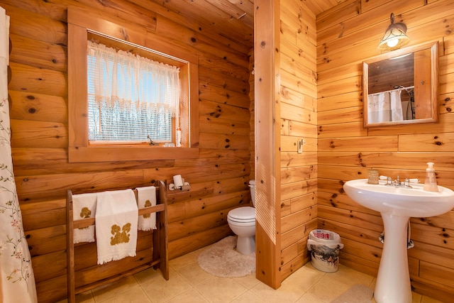 bathroom featuring tile patterned flooring, toilet, and wooden walls