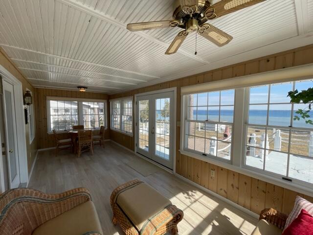 unfurnished sunroom featuring french doors, ceiling fan, and a water view