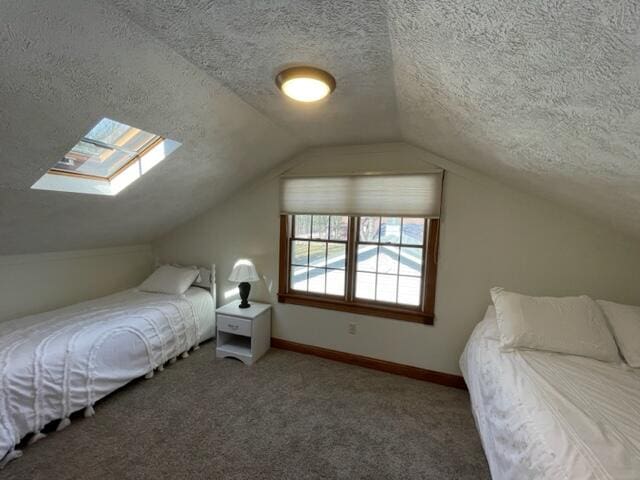 bedroom featuring vaulted ceiling with skylight, dark carpet, and a textured ceiling