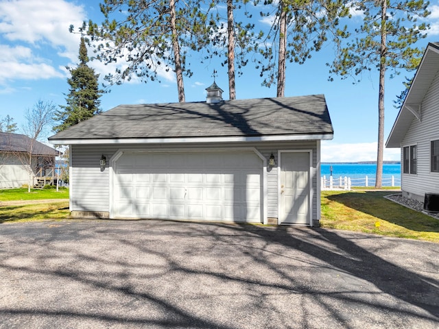 garage with a yard, a water view, and central AC