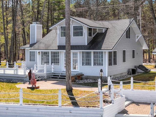 new england style home featuring central AC unit and a front yard