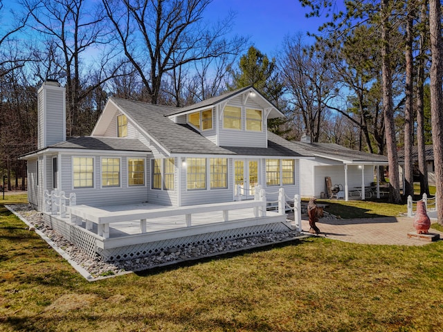 rear view of house with a wooden deck and a lawn