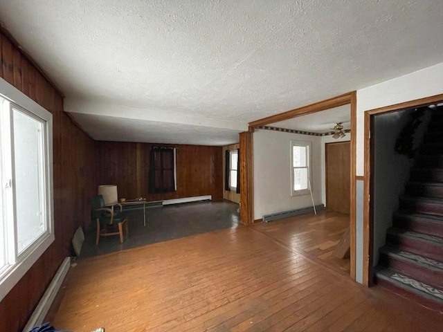 unfurnished living room with hardwood / wood-style flooring, wooden walls, and a textured ceiling