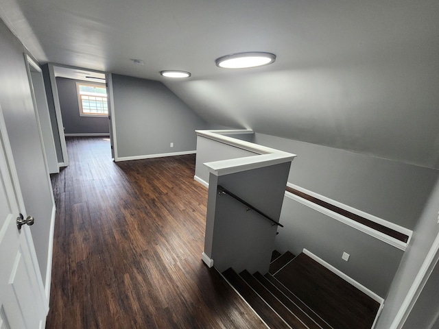 staircase featuring dark wood-type flooring and vaulted ceiling