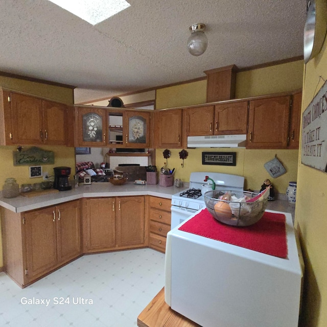 kitchen with a skylight, gas range gas stove, a textured ceiling, and light tile floors