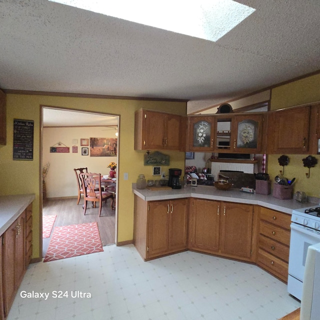 kitchen with lofted ceiling with skylight, a textured ceiling, white range with gas stovetop, and light tile floors